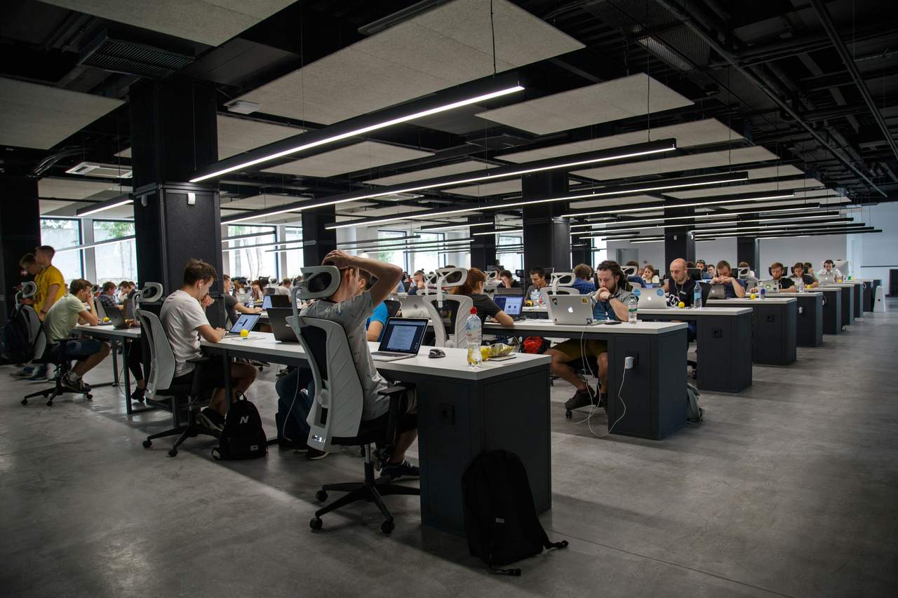 A large open-plan office, rows of identical desks and people